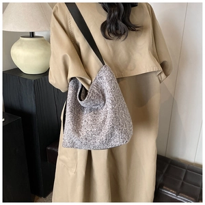 Detail of grey patterned knit crossbody bag textured fabric with black wide shoulder strap