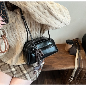 Detail of black glossy PU shoulder bag with brown dog charm and checkerboard pendant