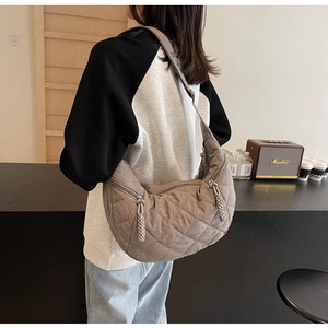 Detail of grey quilted dumpling tote bag featuring double zippers and padded shoulder strap