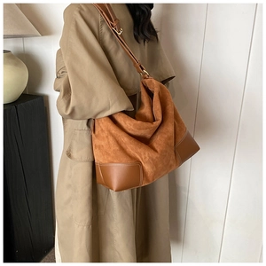 Detail of a large brown suede tote bag styled with a khaki trench coat for an elegant urban look