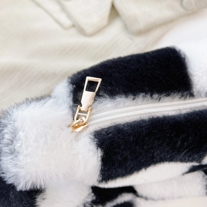 Close-up of black and white faux fur texture with high-quality gold metal zipper puller