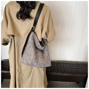 Detail of grey knitted Hobo bag featuring a black leather strap with silver metal buckle