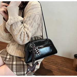 Detail of black glossy shoulder bag with playful chocolate and dachshund charm accessories