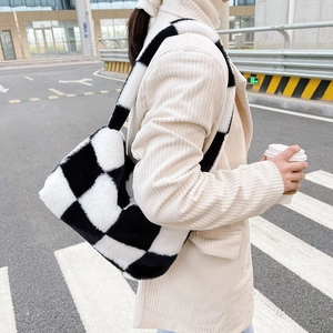 Outdoor street style shot of a plush black and white checkerboard faux fur shoulder bag