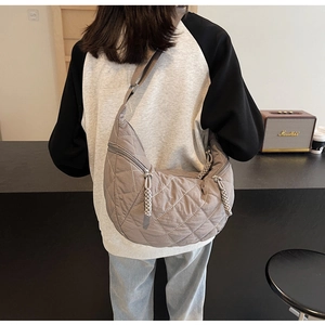 Detailed view of the quilted diamond texture and woven zipper on the grey crescent bag