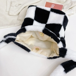 Detail showing plush black and white checkerboard bag with magnetic snap and beige lining