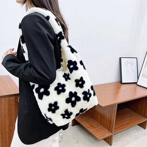 Detail view of a white plush shoulder bag with black flower embroidery for autumn fashion
