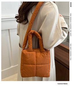 Detail of caramel quilted puff tote bag showing square stitching and wide shoulder strap