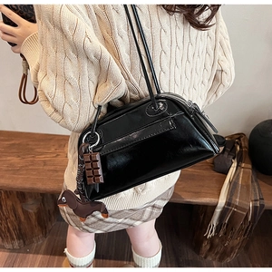 Detail of black glossy shoulder bag featuring silver hardware and a chocolate dog charm