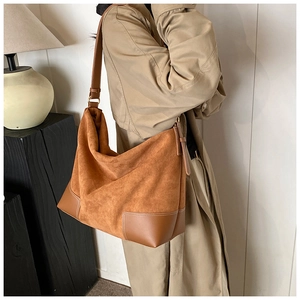 Brown large capacity suede tote bag with leather contrast trim on a model shoulder