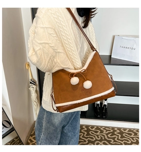 Detail of autumn brown PU leather handbag featuring white faux fur trim and cute fuzzy pom-poms