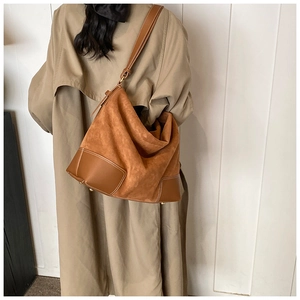 Detail of large brown suede tote bag with contrast stitching on smooth leather bottom