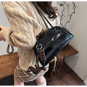 Detail of black patent leather shoulder bag with chocolate and dachshund pendants