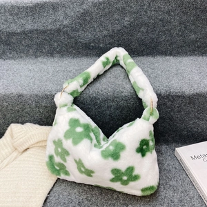 Detail of white plush shoulder bag featuring green floral patterns and gold metal rings