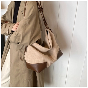 Detail of contrast stitching on the brown leather strap and beige matte canvas tote bag
