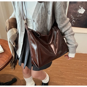 Gros plan d'un sac cabas en similicuir marron foncé poli avec une large bandoulière