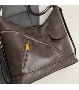 Detail of dark brown vintage PU leather handbag with dual diagonal zippers and soft texture