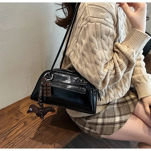 Detail of glossy black PU leather shoulder bag with cute dachshund and chocolate charms