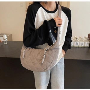 Detail of quilted khaki crescent bag featuring wide shoulder strap and woven zipper pull