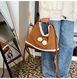 Close-up of brown suede handbag with white faux fur trim and delicate bow detail