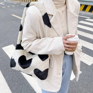 Sac à épaule en peluche à motif cœur avec large bandoulière dans un décor urbain