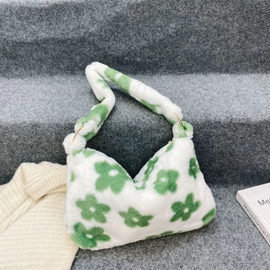 Detail view of plush faux fur handbag with green floral pattern and gold metal ring clips