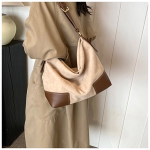 Detail of beige suede hobo bag with dark brown leather trim and adjustable gold buckle