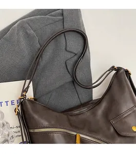 Detail view of adjustable shoulder strap and gold hardware on dark brown matte hobo bag