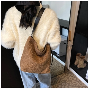 Close-up of brown textured hobo bag with black leather strap for autumn fashion