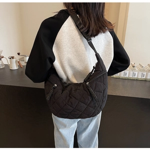 Detail shot of black quilted crescent crossbody bag with adjustable nylon shoulder strap