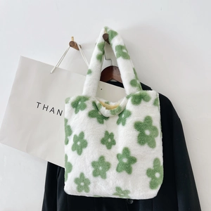 Detail view of plush faux fur tote bag with green floral pattern on white background
