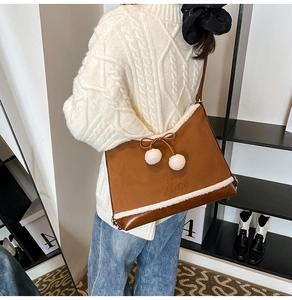 Detail of brown PU crossbody bag featuring soft white faux fur trim and cute pom-pom charms