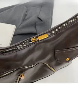 Detailed macro view of high-quality gold hardware zippers on a dark brown PU leather bag