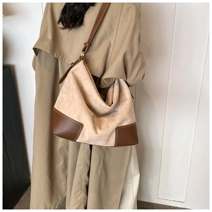 Detail of hobo bag with contrast stitching and beige suede texture on model