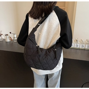Detail of black quilted nylon crescent bag showing diamond texture and adjustable strap