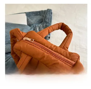 Close-up of caramel quilted puffer bag with high-quality golden metal zipper detail