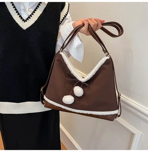 Detail of brown PU crossbody bag featuring soft white faux fur trim and cute plush pom-poms