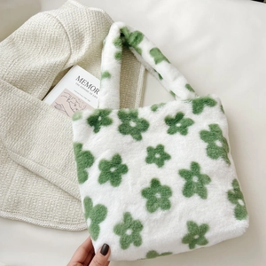 Close-up of a white plush tote bag with green floral patterns and soft faux fur texture