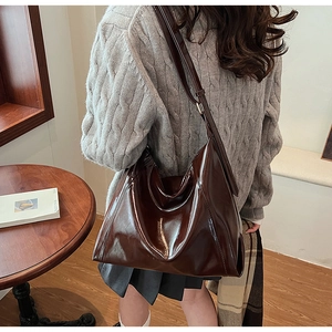 Détail du grand sac porté épaule Hobo en cuir brillant marron foncé sur modèle