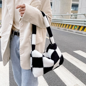 Detail of soft plush shoulder bag featuring a classic black and white checkerboard pattern
