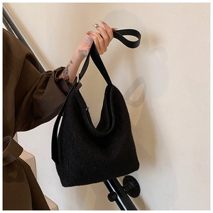 Detail of black faux fur hobo bag with wide strap showing warm winter texture