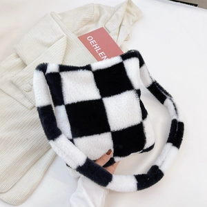 Close-up of black and white checkerboard plush tote bag on white textured fabric