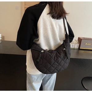 Detail of black quilted puffer crescent bag with stitched diamond patterns and zipper pull