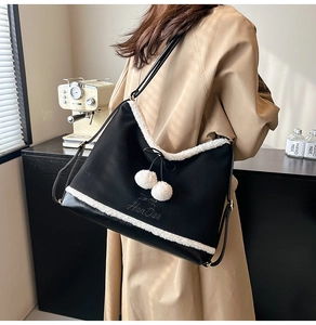 Detail of black PU shoulder bag featuring white sherpa trim and decorative pom-poms