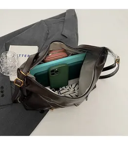 Top view of spacious brown PU leather crossbody bag interior holding a tablet and phone