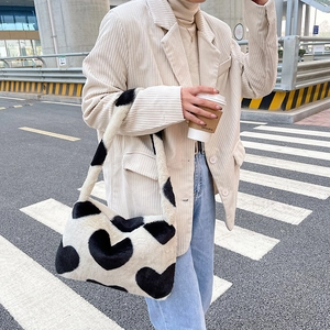 Détail du sac à épaule en peluche avec motif de vache et cœurs dans un style citadin chic