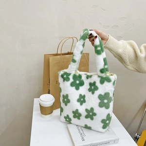 Detail of green and white plush flower tote bag held by hand in a cozy interior setting