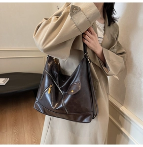 Detail of dark brown faux leather hobo bag with multiple zippers and rivets
