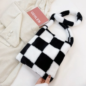 Close-up of fluffy black and white checkered plush handbag on a white minimal desk