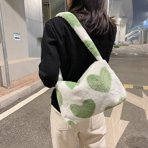Vue détaillée d'un sac à bandoulière en peluche avec motif cœur vert porté par un mannequin
